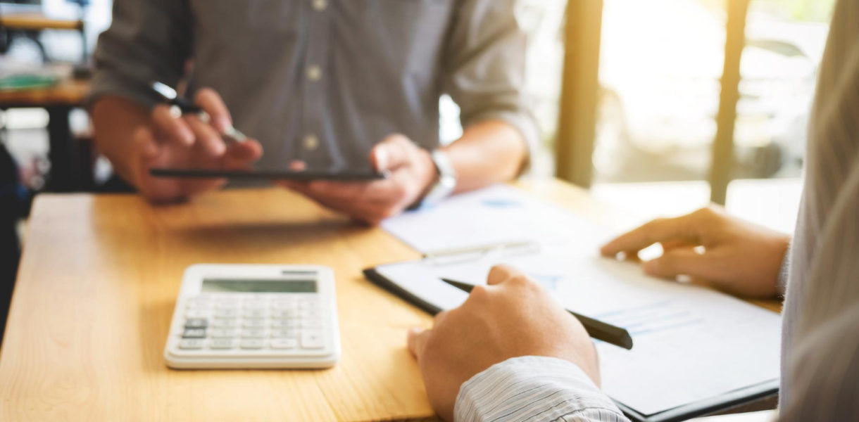 Agent financier analysant les besoins bancaires de clients lors d’une réunion, conseils pour choisir la meilleure banque et services bancaires adaptés.