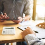 Agent financier analysant les besoins bancaires de clients lors d’une réunion, conseils pour choisir la meilleure banque et services bancaires adaptés.